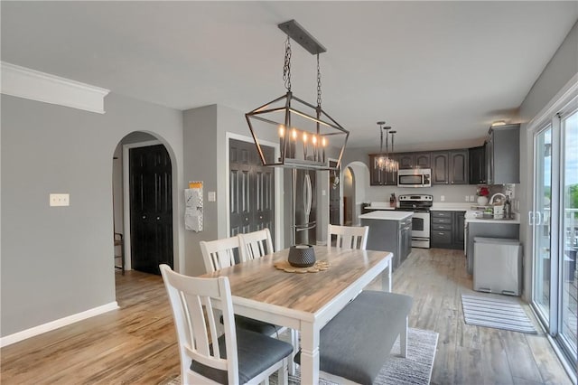 8014 Maureen Dr, Cranberry Twp, PA 16066 - dining space featuring arched walkways, light wood-type flooring, baseboards, and a chandelier