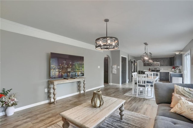 8014 Maureen Dr, Cranberry Twp, PA 16066 - living room with arched walkways, a chandelier, light wood-style floors, and baseboards