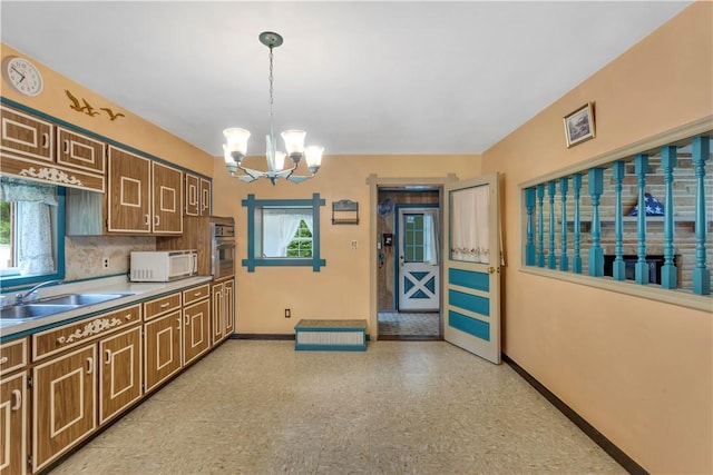 427 Harpers Ferry Rd, North Sewickley Twp, PA 15010 - kitchen featuring white microwave, baseboards, a chandelier, hanging light fixtures, and a sink