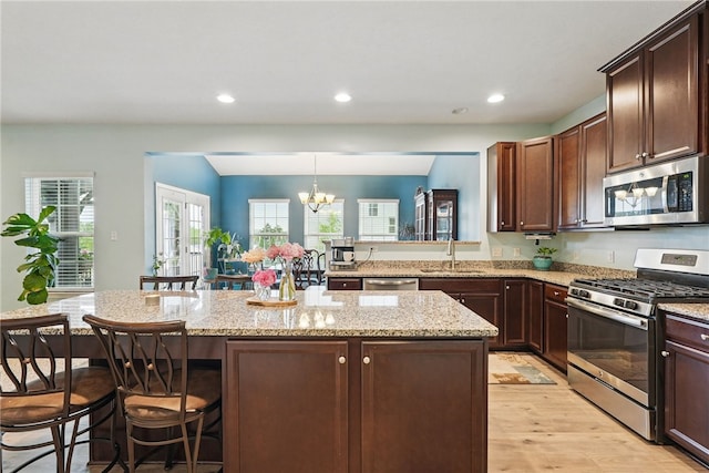 407 Isabella Ct, Zelienople Boro, PA 16063 - kitchen featuring appliances with stainless steel finishes, a sink, a chandelier, a breakfast bar, and light wood-type flooring