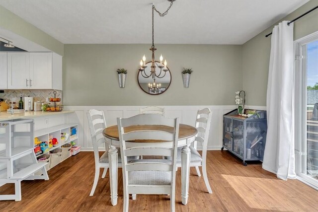 309 Wildflower Ct, Ross Twp, PA 15202 - dining room featuring light wood-type flooring, a chandelier, a wainscoted wall, and a decorative wall