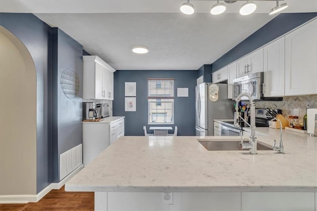 309 Wildflower Ct, Ross Twp, PA 15202 - kitchen featuring stainless steel appliances, light stone counters, white cabinetry, a peninsula, and decorative backsplash