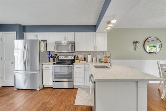 309 Wildflower Ct, Ross Twp, PA 15202 - kitchen with appliances with stainless steel finishes, a sink, a peninsula, white cabinets, and light wood-style flooring