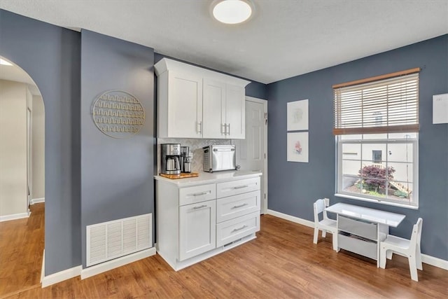 309 Wildflower Ct, Ross Twp, PA 15202 - kitchen with arched walkways, light wood-style flooring, white cabinets, and baseboards