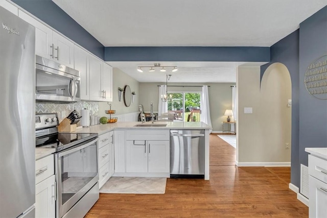 309 Wildflower Ct, Ross Twp, PA 15202 - kitchen with appliances with stainless steel finishes, a peninsula, a sink, light wood-type flooring, and light countertops