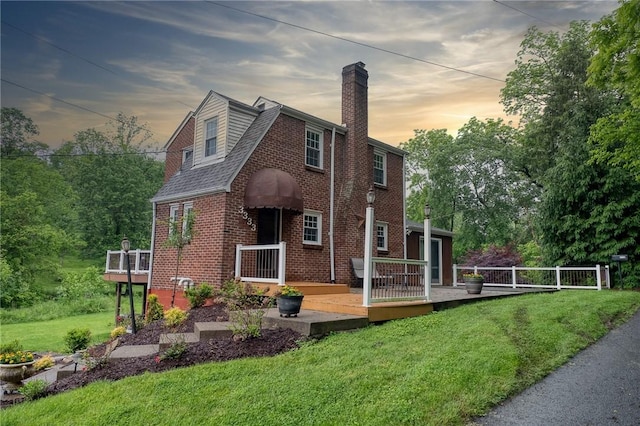 3333 Walther Ln, Upper St Clair, PA 15241 - back of property at dusk with brick siding, a wooden deck, a chimney, and a lawn