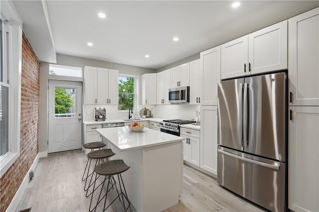 346 45th St, Lawrenceville, PA 15201 - kitchen with appliances with stainless steel finishes, a sink, brick wall, a breakfast bar area, and a center island