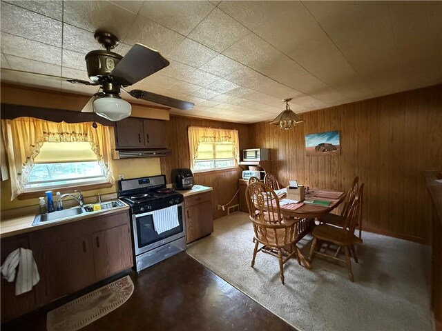 201 Lebanon Manor Dr, West Mifflin, PA 15122 - kitchen featuring stainless steel appliances, exhaust hood, a sink, wooden walls, and light countertops