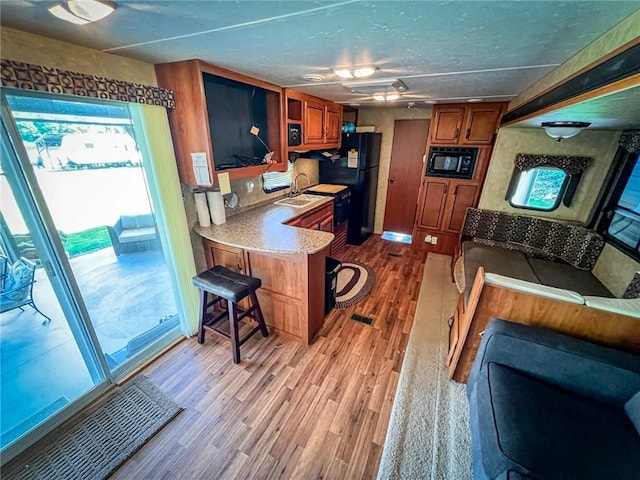 126 Dockside Ln, Bradys Bend Twp, PA 16028 - kitchen featuring black appliances, brown cabinets, light wood finished floors, light countertops, and a textured ceiling