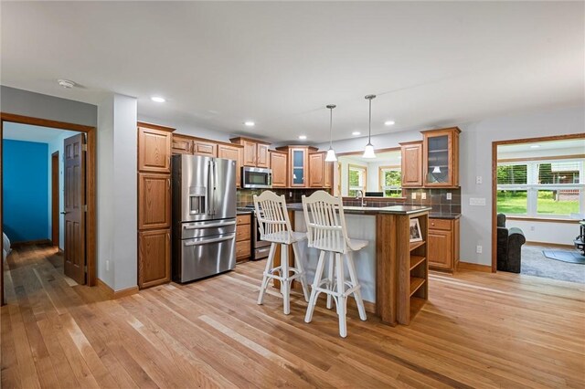 310 Laurel Ln, Leeper, PA 16233 - kitchen with appliances with stainless steel finishes, brown cabinetry, light wood-style floors, a kitchen bar, and backsplash