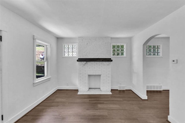 8536 Pershing St, Penn Hills, PA 15235 - unfurnished living room with a fireplace, plenty of natural light, arched walkways, and wood finished floors