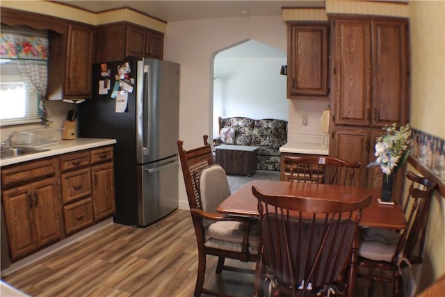 84 Pennsylvania Ave, Monessen, PA 15062 - kitchen featuring freestanding refrigerator, light wood finished floors, light countertops, a sink, and arched walkways