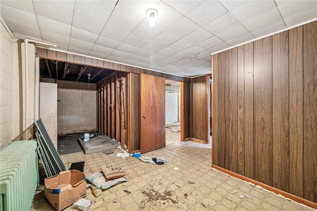308 Cypress St, Rostraver, PA 15089 - finished below grade area with radiator heating unit, tile patterned floors, wooden walls, and concrete block wall