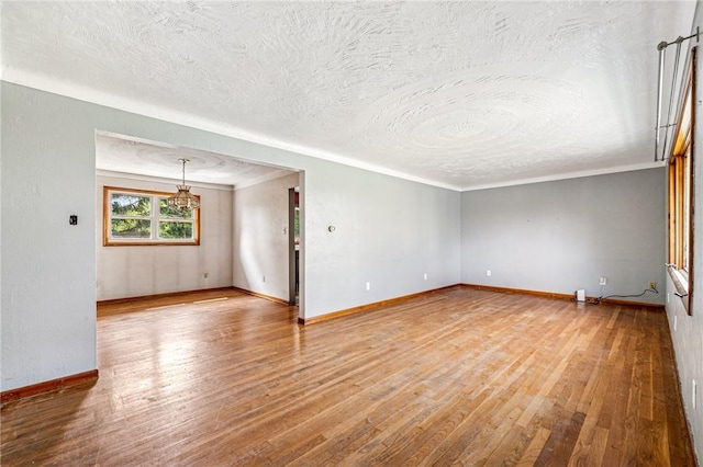 308 Cypress St, Rostraver, PA 15089 - empty room with a textured ceiling, wood finished floors, baseboards, ornamental molding, and a chandelier