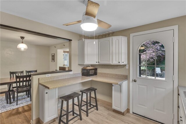 2389 High Oak Dr, Banksville/Westwood, PA 15220 - kitchen featuring light wood-style flooring, black microwave, white cabinetry, a breakfast bar, and ceiling fan