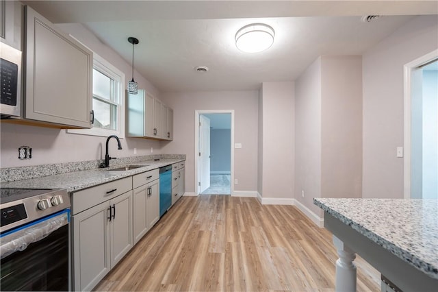 1200 Wood St, Derry Twp, PA 15650 - kitchen featuring stainless steel appliances, a sink, light wood finished floors, decorative light fixtures, and light stone counters