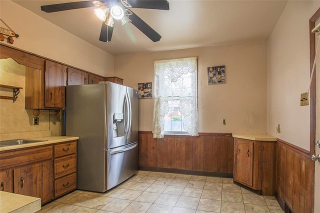 202 Jane St, Mckees Rocks, PA 15136 - kitchen featuring stainless steel refrigerator with ice dispenser, a wainscoted wall, brown cabinetry, wooden walls, and a ceiling fan