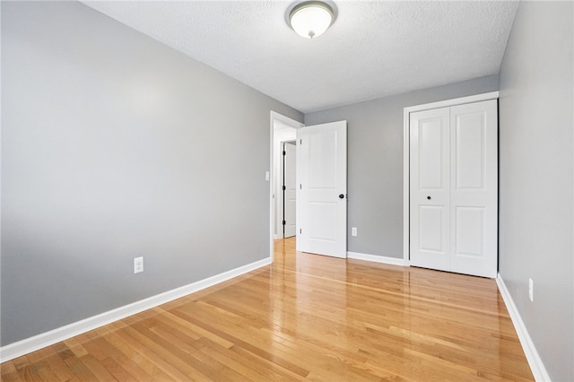 450 Limestone Dr, Bethel Park, PA 15102 - unfurnished bedroom with light wood-type flooring, baseboards, a textured ceiling, and a closet