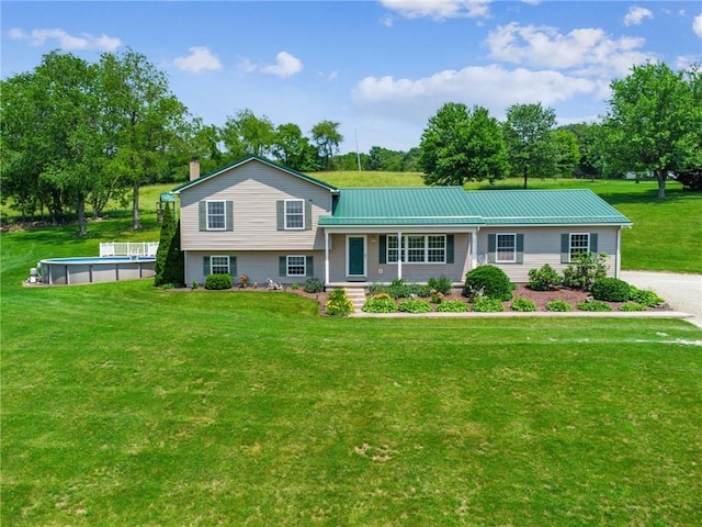 142 Poorbaugh Rd, Bullskin Twp, PA 15425 - tri-level home with an outdoor pool, a front lawn, a metal roof, a chimney, and covered porch