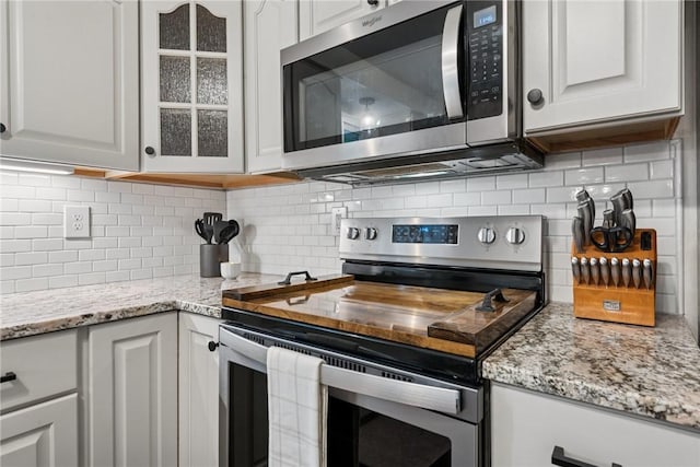 1703 Barry Dr, North Huntingdon, PA 15642 - kitchen with stainless steel appliances, white cabinetry, backsplash, glass insert cabinets, and light stone countertops