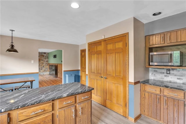206 Brook Hollow Rd, Pa, PA 15666 - kitchen featuring stainless steel microwave, tasteful backsplash, light wood-style flooring, dark stone counters, and decorative light fixtures