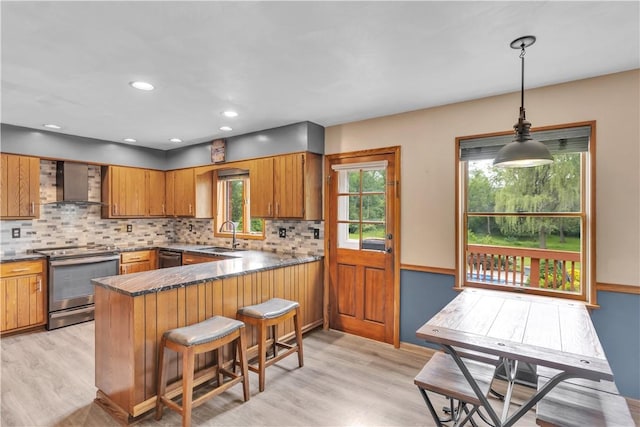 206 Brook Hollow Rd, Pa, PA 15666 - kitchen featuring appliances with stainless steel finishes, wall chimney exhaust hood, brown cabinets, light wood-type flooring, and a peninsula