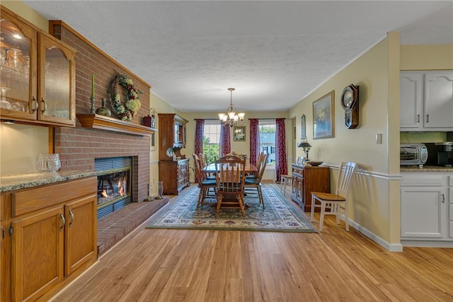117 Bayberry Ln, Cranberry Twp, PA 16066 - dining area with light wood-style flooring, a chandelier, a textured ceiling, and a brick fireplace