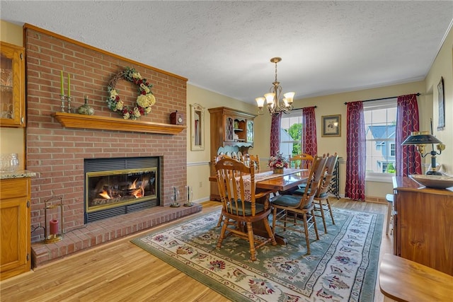 117 Bayberry Ln, Cranberry Twp, PA 16066 - dining space featuring a textured ceiling, light wood-style floors, a chandelier, a fireplace, and baseboards