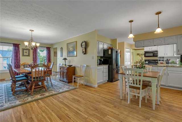 117 Bayberry Ln, Cranberry Twp, PA 16066 - dining area with a chandelier, light wood-type flooring, a textured ceiling, and baseboards