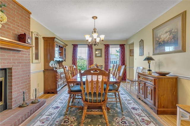 117 Bayberry Ln, Cranberry Twp, PA 16066 - dining room with a chandelier, light wood-type flooring, a textured ceiling, a fireplace, and crown molding
