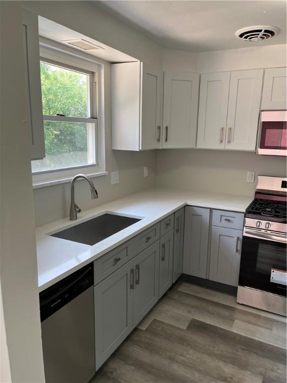 10807 Highpoint Dr, Penn Hills, PA 15235 - kitchen with stainless steel appliances, a sink, light wood-style flooring, and light countertops