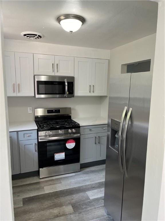 10807 Highpoint Dr, Penn Hills, PA 15235 - kitchen featuring appliances with stainless steel finishes, light wood-type flooring, light countertops, white cabinetry, and gray cabinets