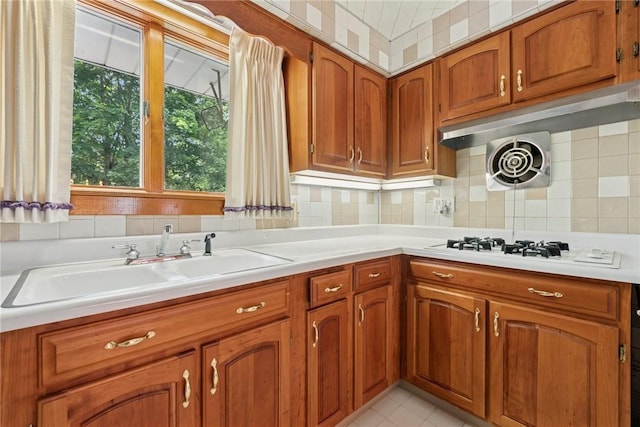 1341 Foxboro Dr, Monroeville, PA 15146 - kitchen with brown cabinets, light countertops, a sink, decorative backsplash, and white gas cooktop