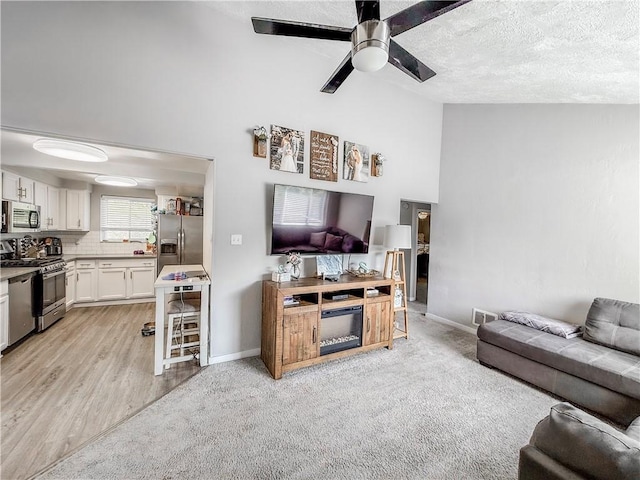 2787 Queensboro Ave, Baldwin Twp, PA 15226 - living area with a ceiling fan, high vaulted ceiling, baseboards, a textured ceiling, and light wood-style flooring