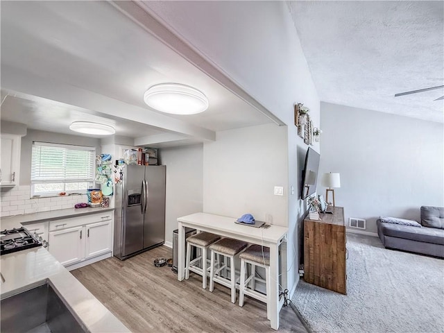 2787 Queensboro Ave, Baldwin Twp, PA 15226 - kitchen featuring stainless steel refrigerator with ice dispenser, white cabinets, light wood finished floors, tasteful backsplash, and open floor plan