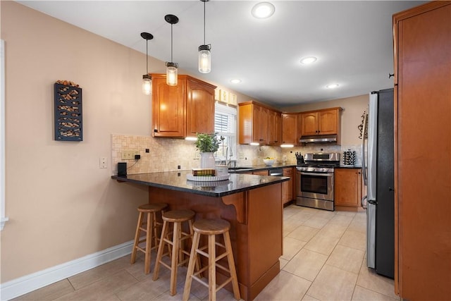 1299 Oakridge Rd, South Fayette, PA 15057 - kitchen featuring appliances with stainless steel finishes, under cabinet range hood, a peninsula, tasteful backsplash, and a kitchen breakfast bar