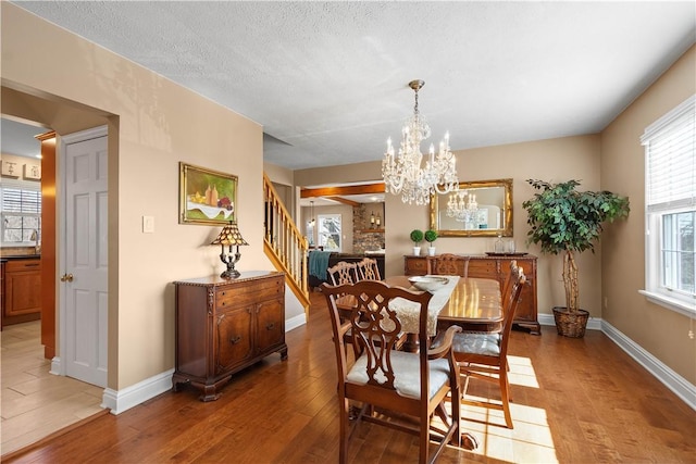 1299 Oakridge Rd, South Fayette, PA 15057 - dining space with light wood-style floors, stairs, a chandelier, baseboards, and a textured ceiling
