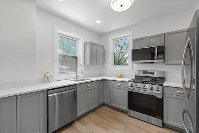 8952 Eastwood Rd, Penn Hills, PA 15235 - kitchen featuring stainless steel appliances, gray cabinetry, a sink, and light wood-style floors