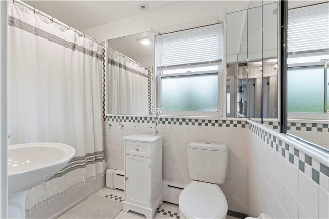 503 6th St, Oakmont, PA 15139 - full bathroom featuring plenty of natural light, baseboard heating, tile walls, and toilet