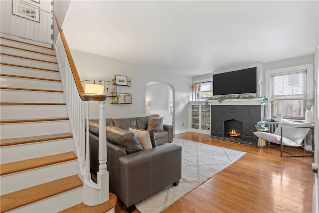 503 6th St, Oakmont, PA 15139 - living room featuring arched walkways, stairway, wood finished floors, and a fireplace with flush hearth