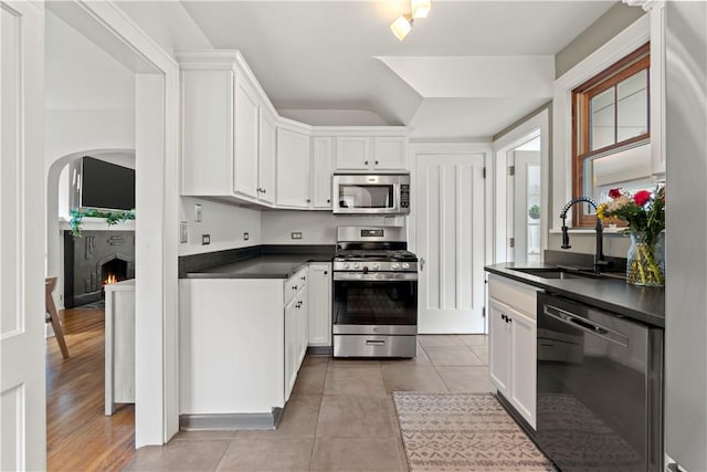 503 6th St, Oakmont, PA 15139 - kitchen with appliances with stainless steel finishes, a sink, arched walkways, dark countertops, and white cabinetry