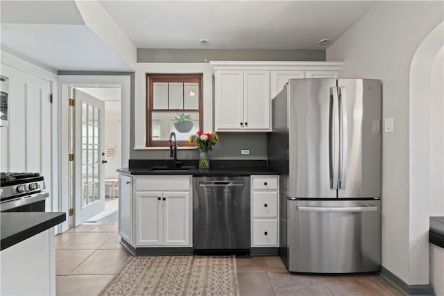 503 6th St, Oakmont, PA 15139 - kitchen featuring appliances with stainless steel finishes, a sink, dark countertops, arched walkways, and white cabinetry