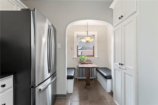 503 6th St, Oakmont, PA 15139 - kitchen with freestanding refrigerator, arched walkways, white cabinets, dark countertops, and tile patterned flooring