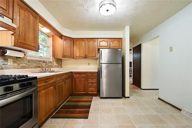 662 Huntington Dr, Cranberry Twp, PA 16066 - kitchen featuring appliances with stainless steel finishes, brown cabinetry, light countertops, a textured ceiling, and under cabinet range hood