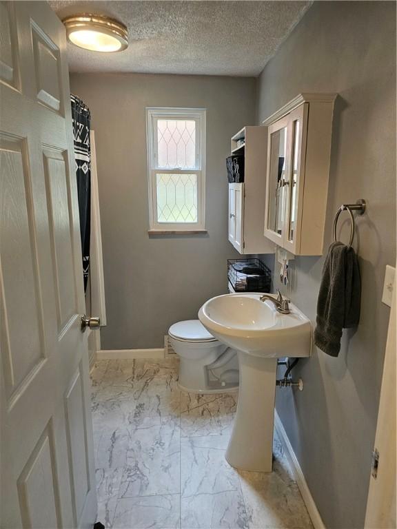 1099 Vine St, Coraopolis, PA 15108 - full bath featuring marble look tiles, baseboards, toilet, a textured ceiling, and a sink
