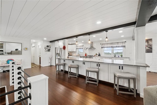 155 Pride Dr, Rostraver, PA 15012 - kitchen with white cabinetry, wall chimney range hood, a kitchen breakfast bar, dark wood-style flooring, and light stone countertops