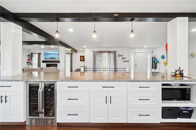 155 Pride Dr, Rostraver, PA 15012 - kitchen with wine cooler, stainless steel microwave, white cabinetry, light stone counters, and open floor plan