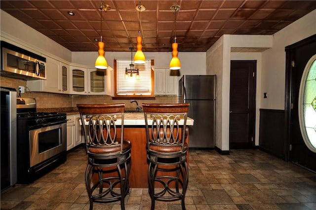 232 Center Ave, Elizabeth Twp/Boro, PA 15037 - kitchen with appliances with stainless steel finishes, stone tile floors, glass insert cabinets, a kitchen island, and backsplash
