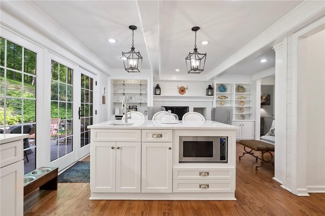 306 Wildberry Rd, Fox Chapel, PA 15238 - kitchen with stainless steel microwave, a sink, light wood-type flooring, pendant lighting, and white cabinets