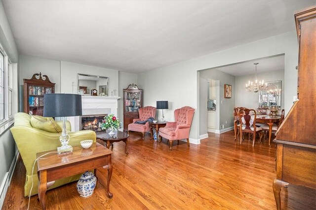 109 Parkview Rd, Ross Twp, PA 15237 - living room featuring a chandelier, light wood-style floors, a glass covered fireplace, and baseboards
